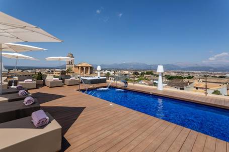 A swimming pool lined with decking, with a view over the town