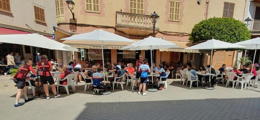 A cafe, with cyclists sitting at tables outside