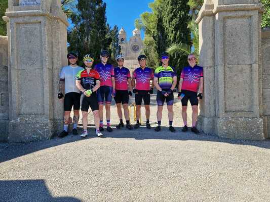 7 cyclists standing next to a tall wall