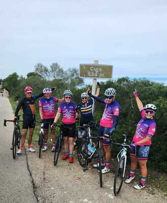6 cyclists pointing to the Cura summit sign