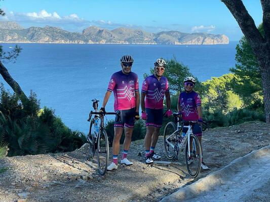 3 cyclists standing in front of a view of the sea