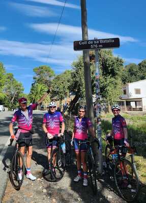 4 cyclists in front of the Col de sa Batalia summit sign